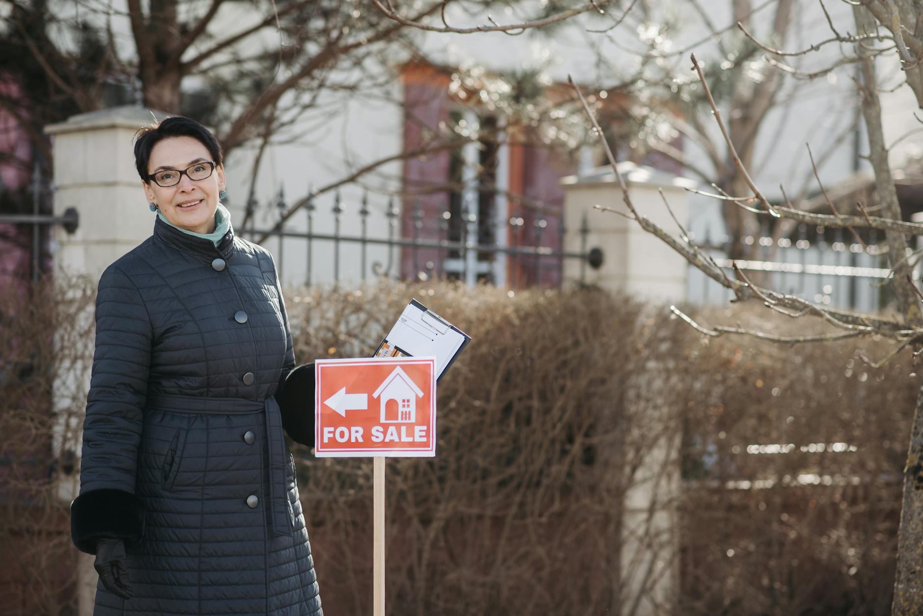 A businesswoman holding 'Sale Pending' and 'Sold' signs indicating a successful real estate transaction.