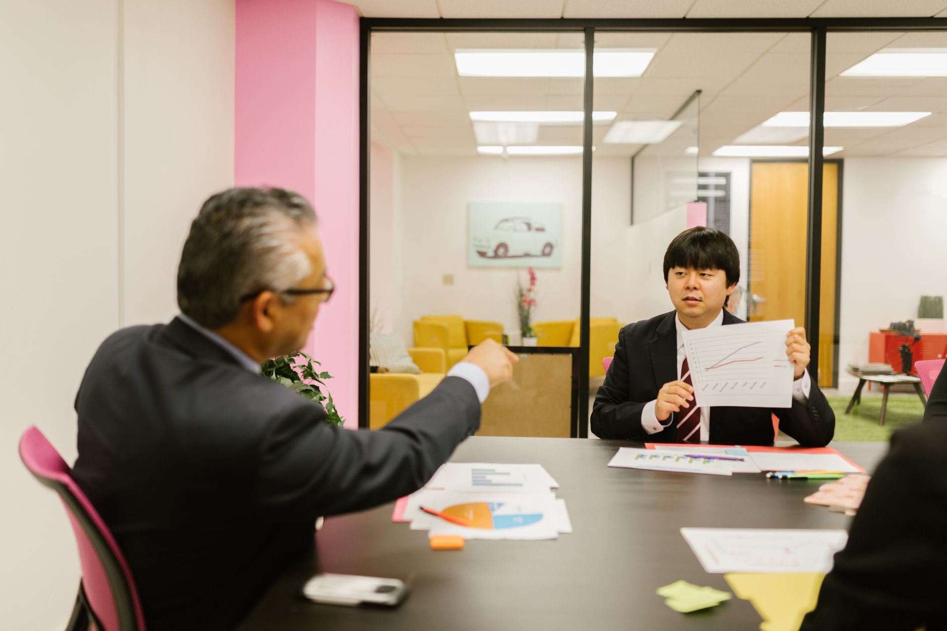 Professionals discussing data charts during a business meeting in a modern office setting.
