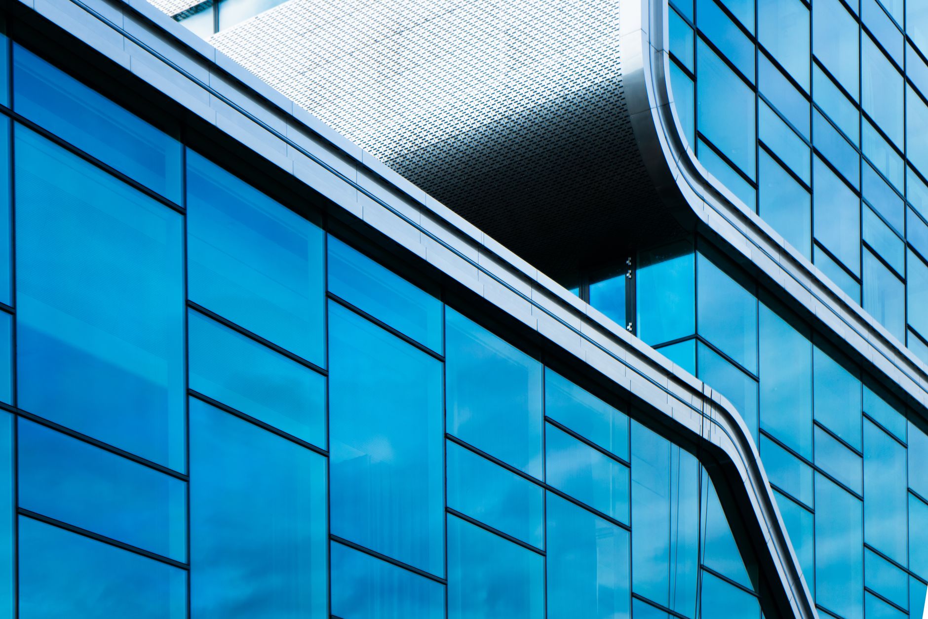 Sleek modern building facade with blue glass and curved metal lines, showcasing abstract design.