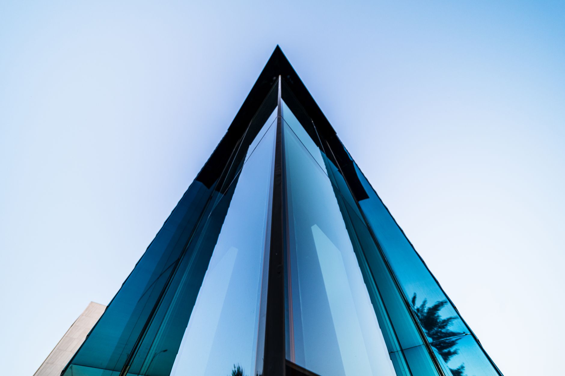 From below of corner of contemporary skyscraper exterior with shiny walls under blue sky in town
