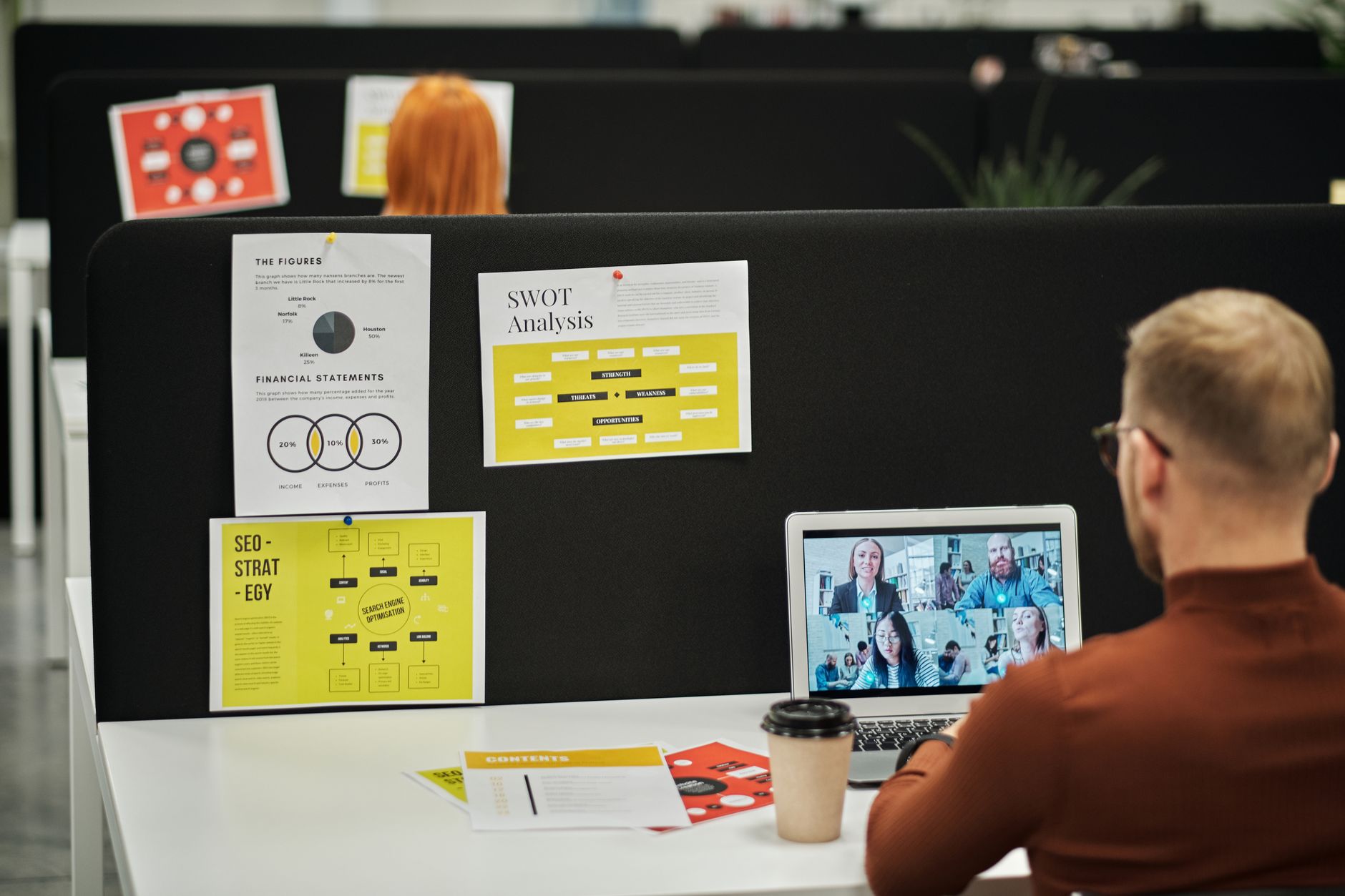 Business meeting over video call in modern office with charts and documents.