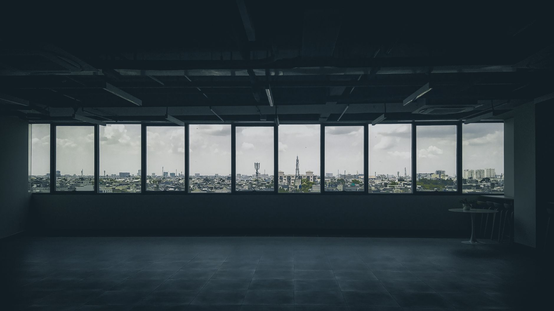 Spacious empty loft with a panoramic view of Ho Chi Minh City skyline through large windows.