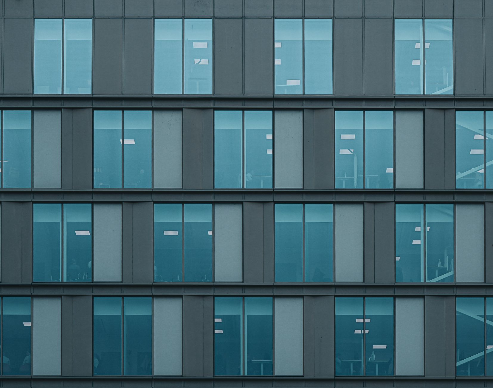 Facade of a modern office building with reflective glass windows creating a geometric pattern.