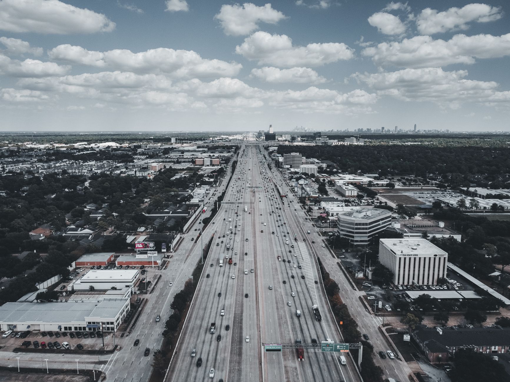 Aerial view of a bustling urban highway with vehicles and buildings, capturing city life and transportation.