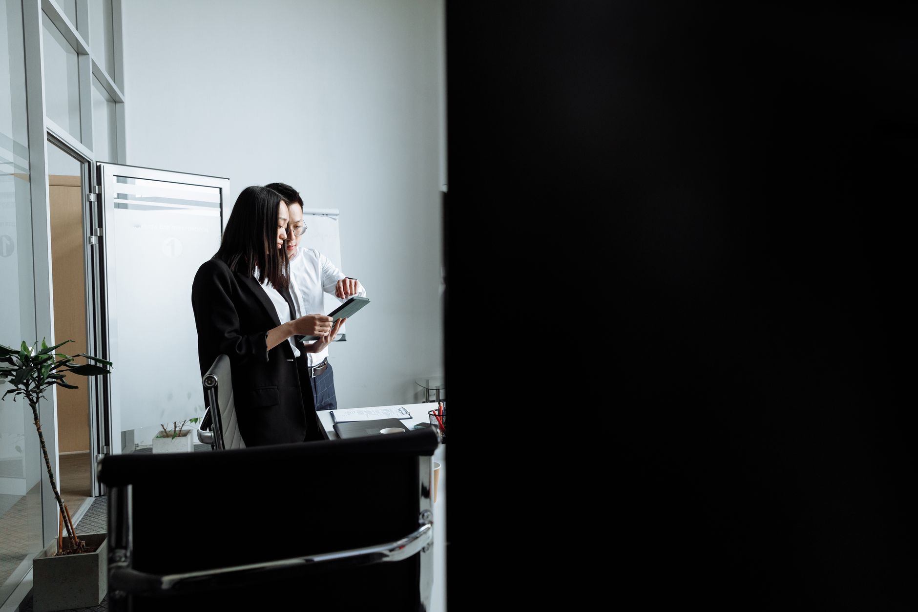 Two young professionals collaborating and discussing work in a modern office setting.