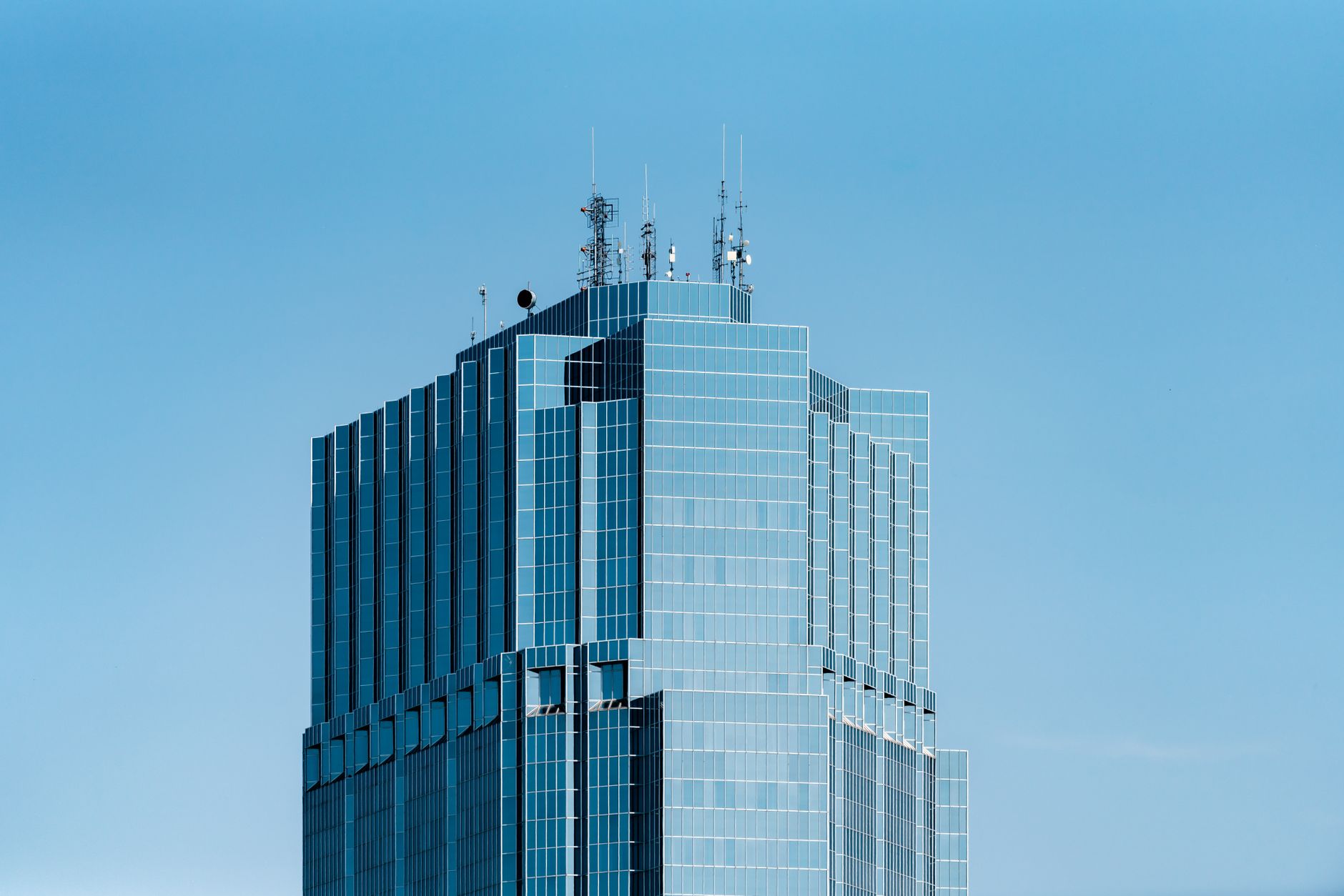 Modern skyscraper with glass facade in London, Ontario, under a clear blue sky.