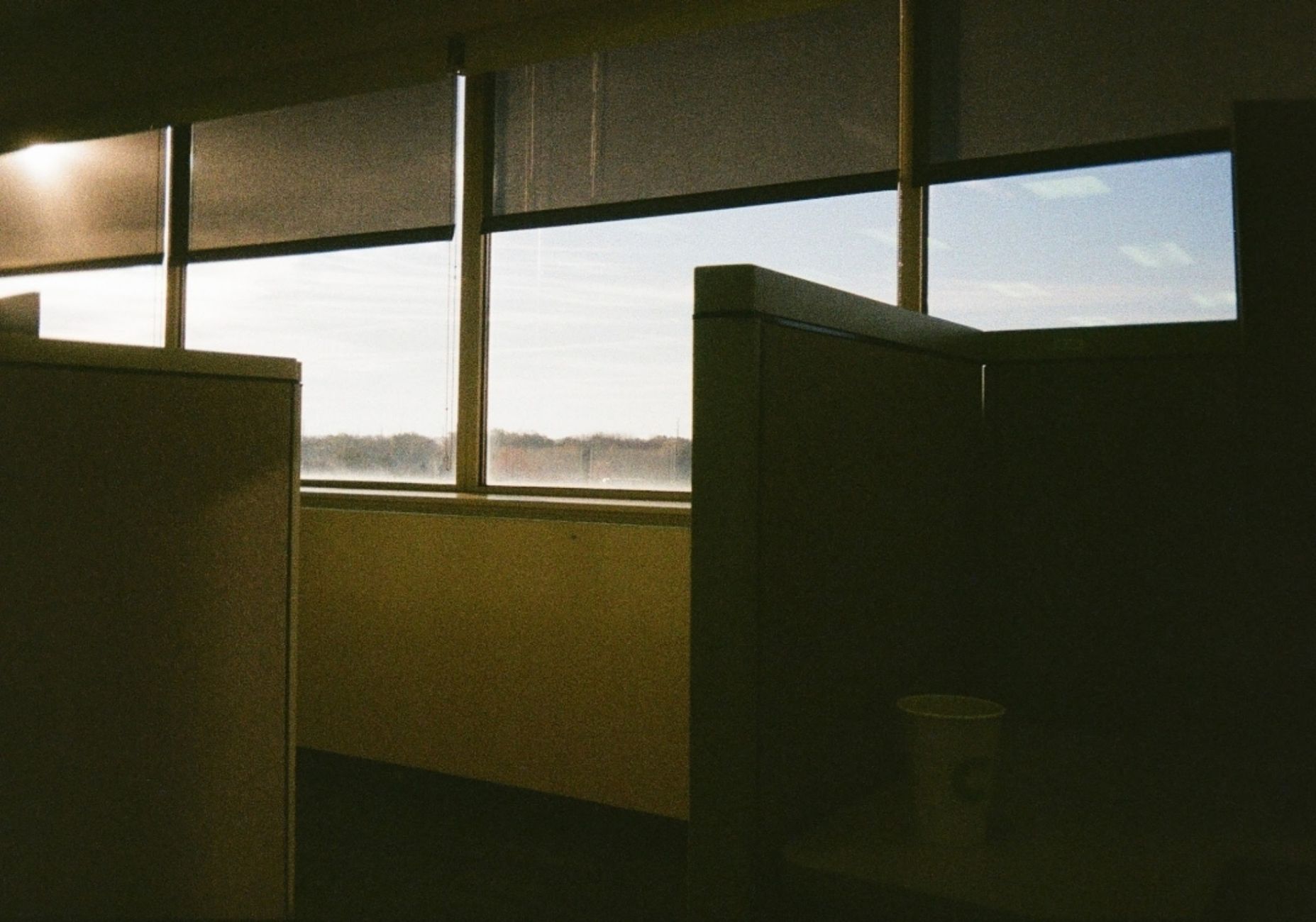 An empty office cubicle with a window view at sunrise in Bloomington, IL.