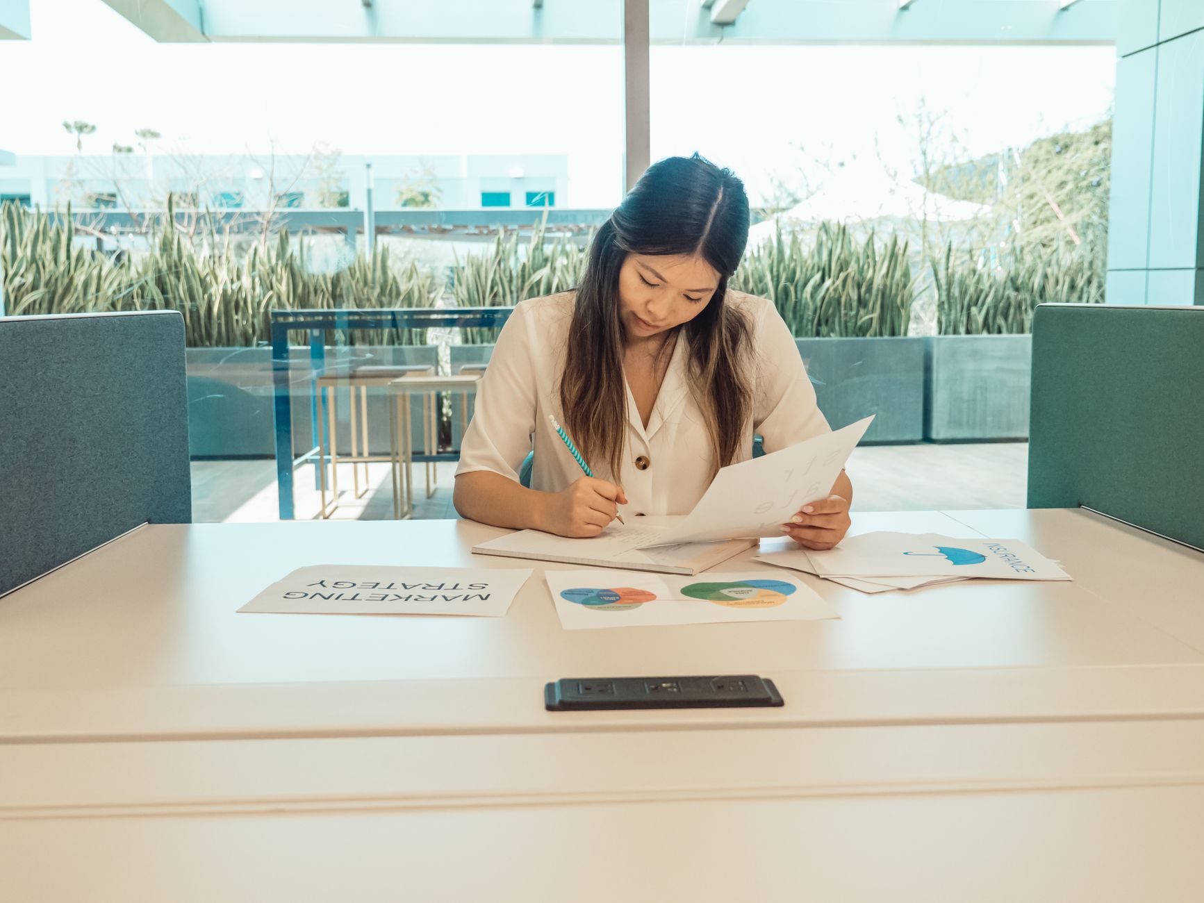 Focused woman working on marketing strategy at desk in modern office setting.