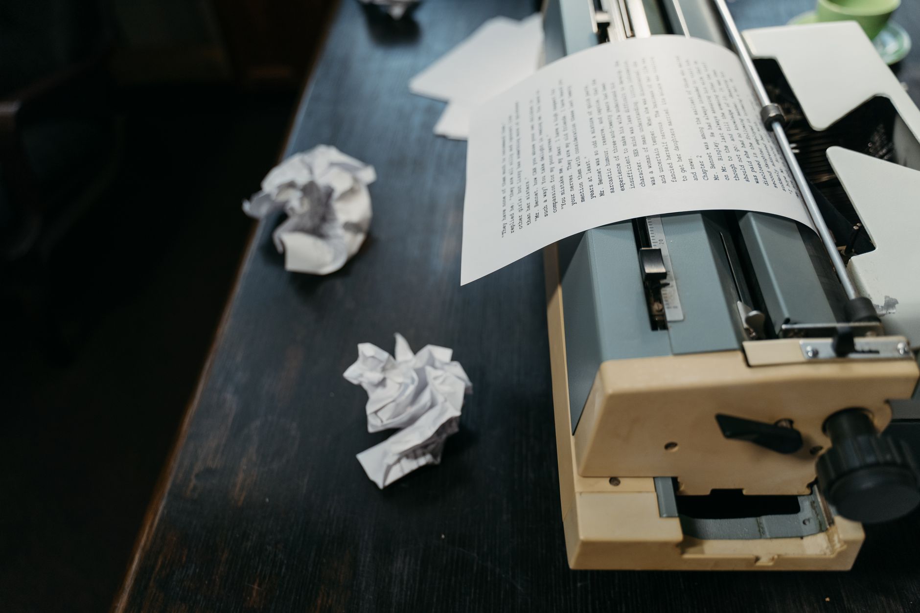 A close-up of a vintage typewriter with crumpled papers on a wooden desk, evoking a sense of creativity and nostalgia.