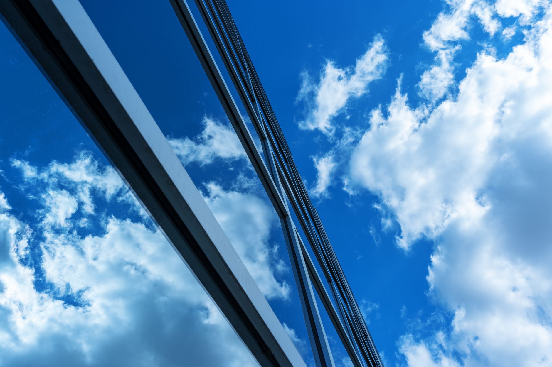 A sleek modern building with reflective glass windows and a clear blue sky with clouds.