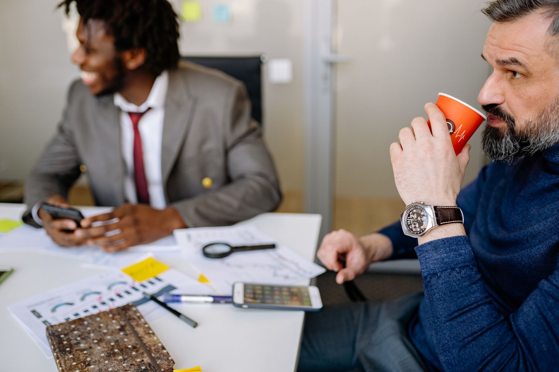 Two business professionals sharing a casual moment over coffee in an office environment.