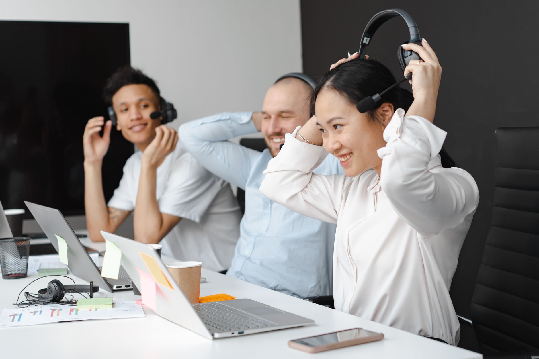 Group of diverse coworkers collaborating in a call center setting, wearing headsets and working together.