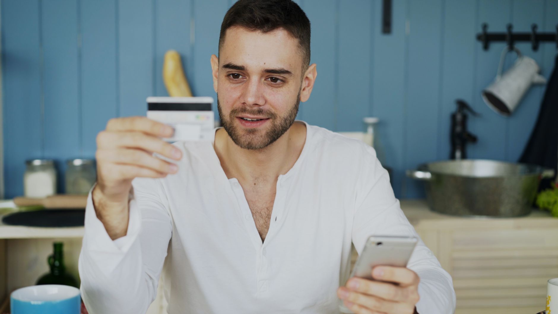 Man holding credit card and smartphone, shopping online at home.