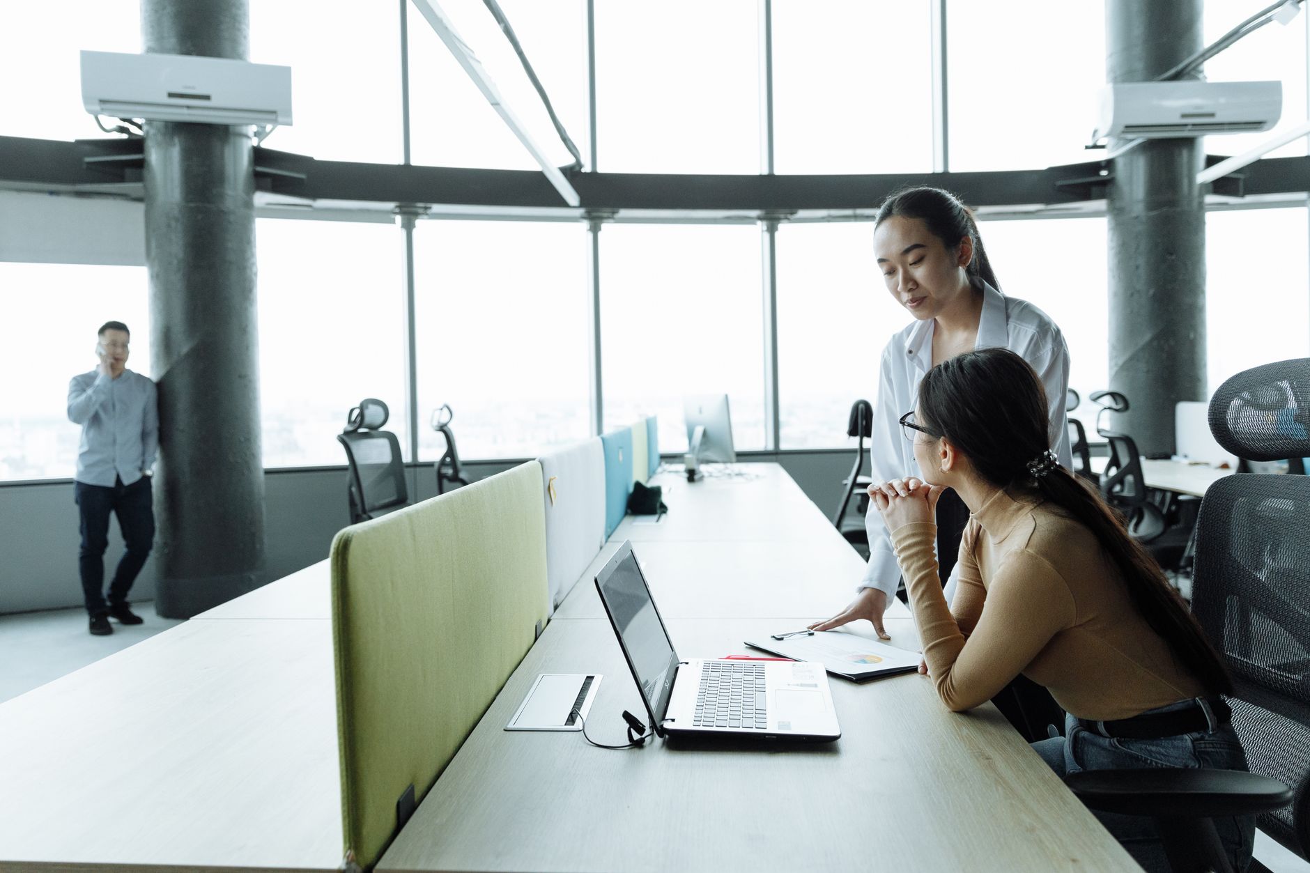 Colleagues collaborating in a spacious, well-lit office with laptops.