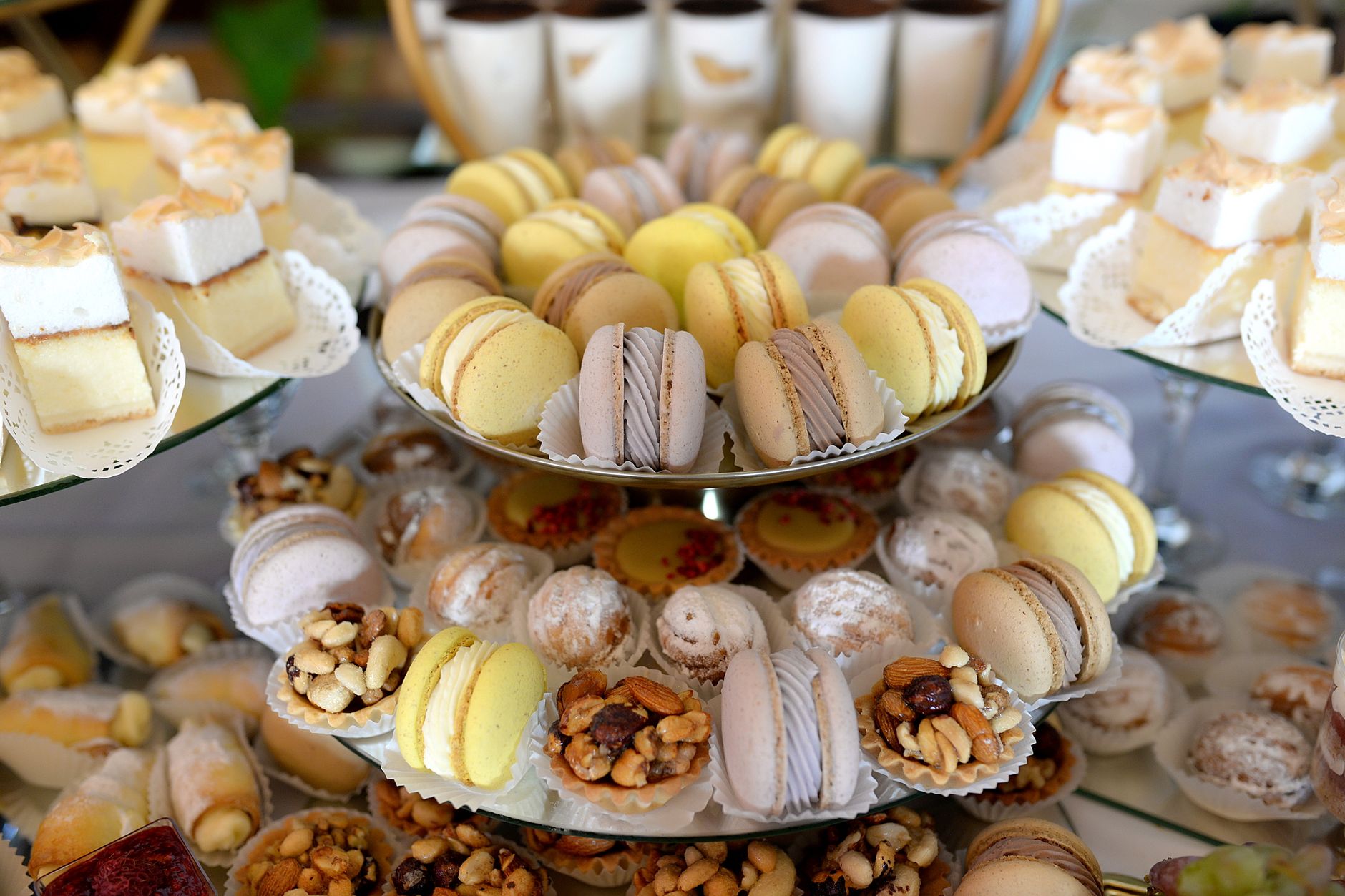 A lavish display of colorful macarons and assorted pastries on a tiered dessert platter.