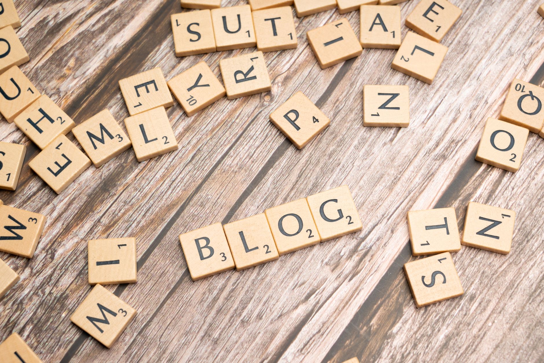 Scattered wooden letter tiles spelling 'Blog' on a rustic wood background.
