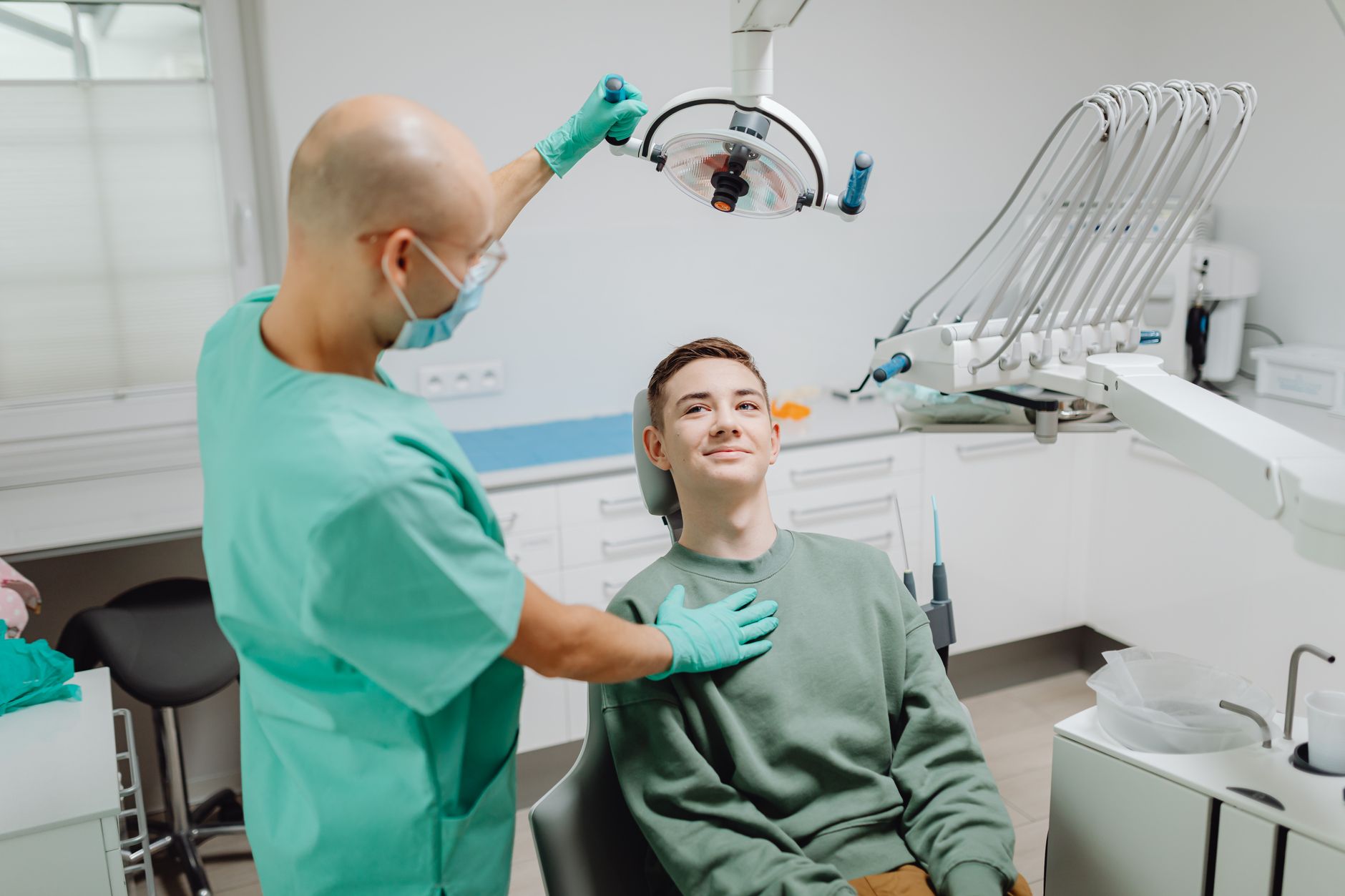 Dentist examining a patient under dental light in a modern clinic setting.