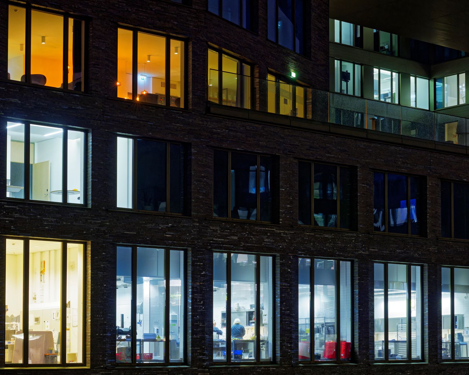 Night view of a modern office building facade with illuminated windows showcasing varied interior lighting.