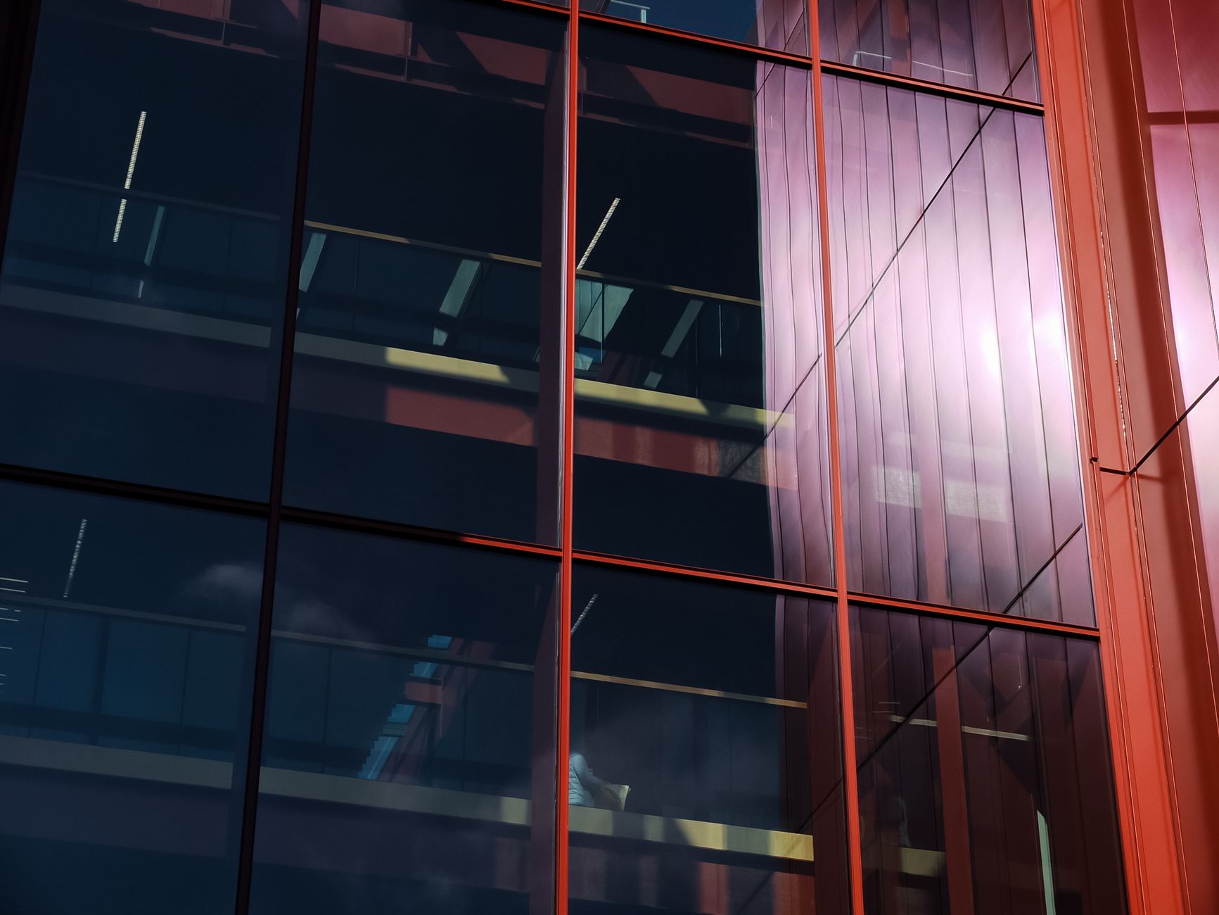 Close-up view of a modern glass facade reflecting sunlight with urban architectural details.