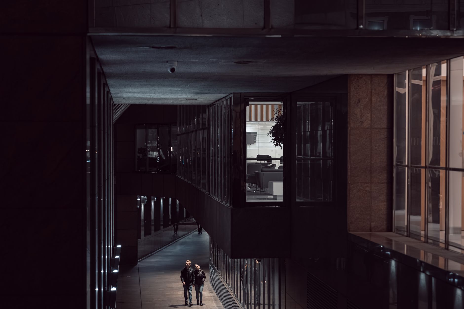 People walking in a modern architectural alley at night in London, England.