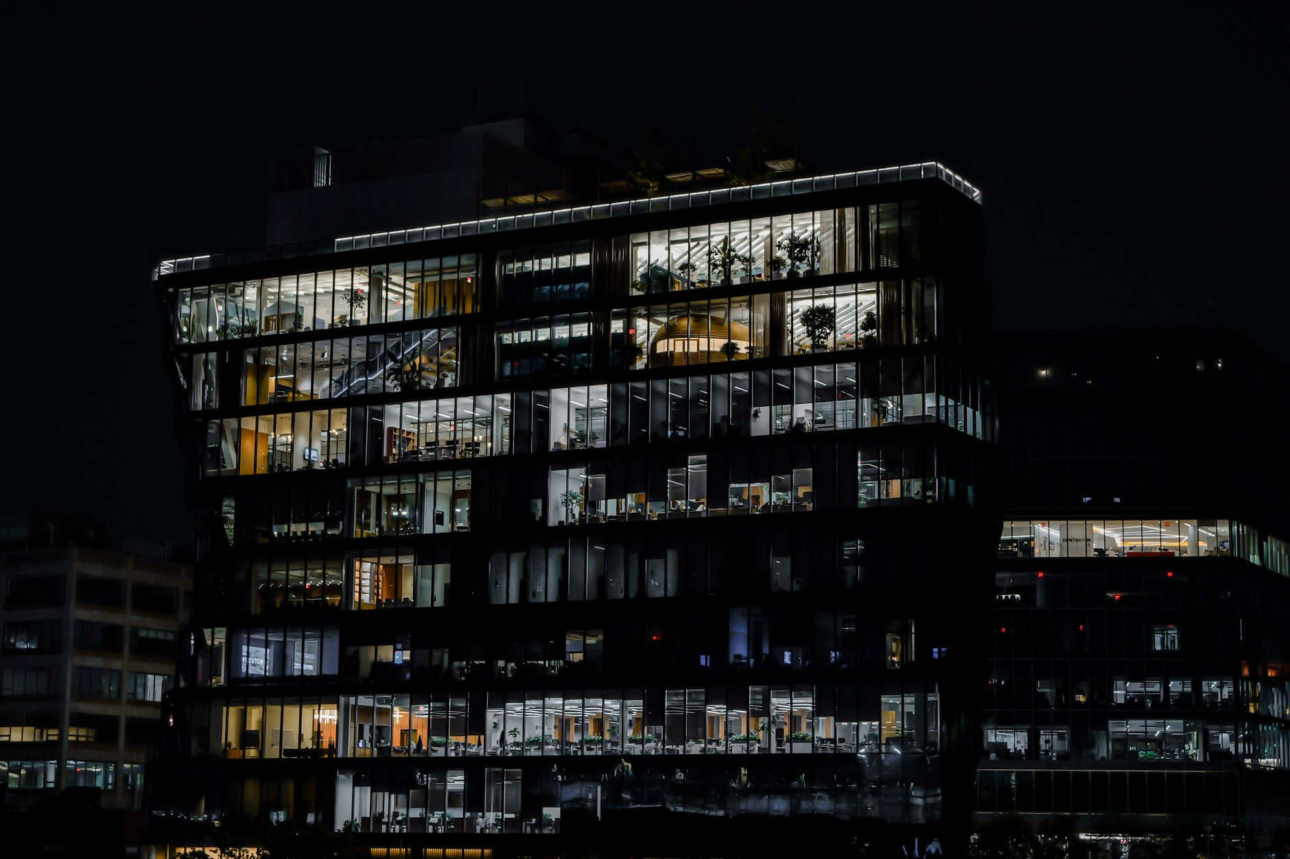 A captivating image of a contemporary office building illuminated against the night sky, showcasing urban architecture.