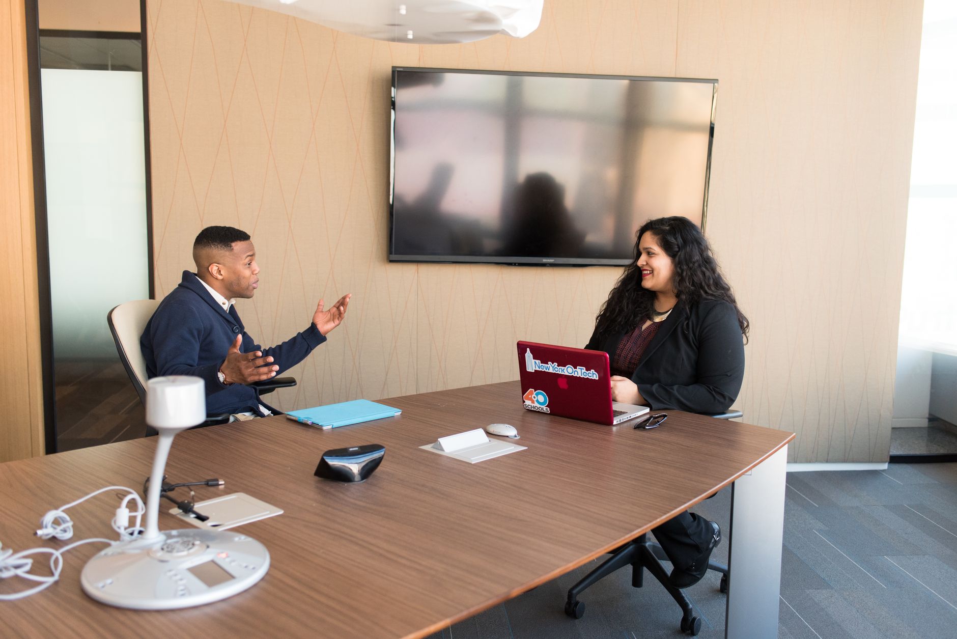 Two professionals discussing in a modern office with laptops and smart technology.