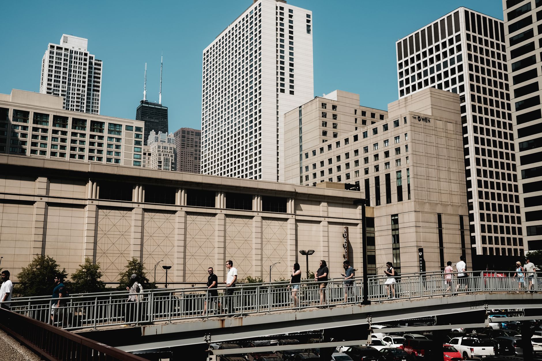 People crossing a bridge with the skyscrapers of Chicago's skyline in the background.