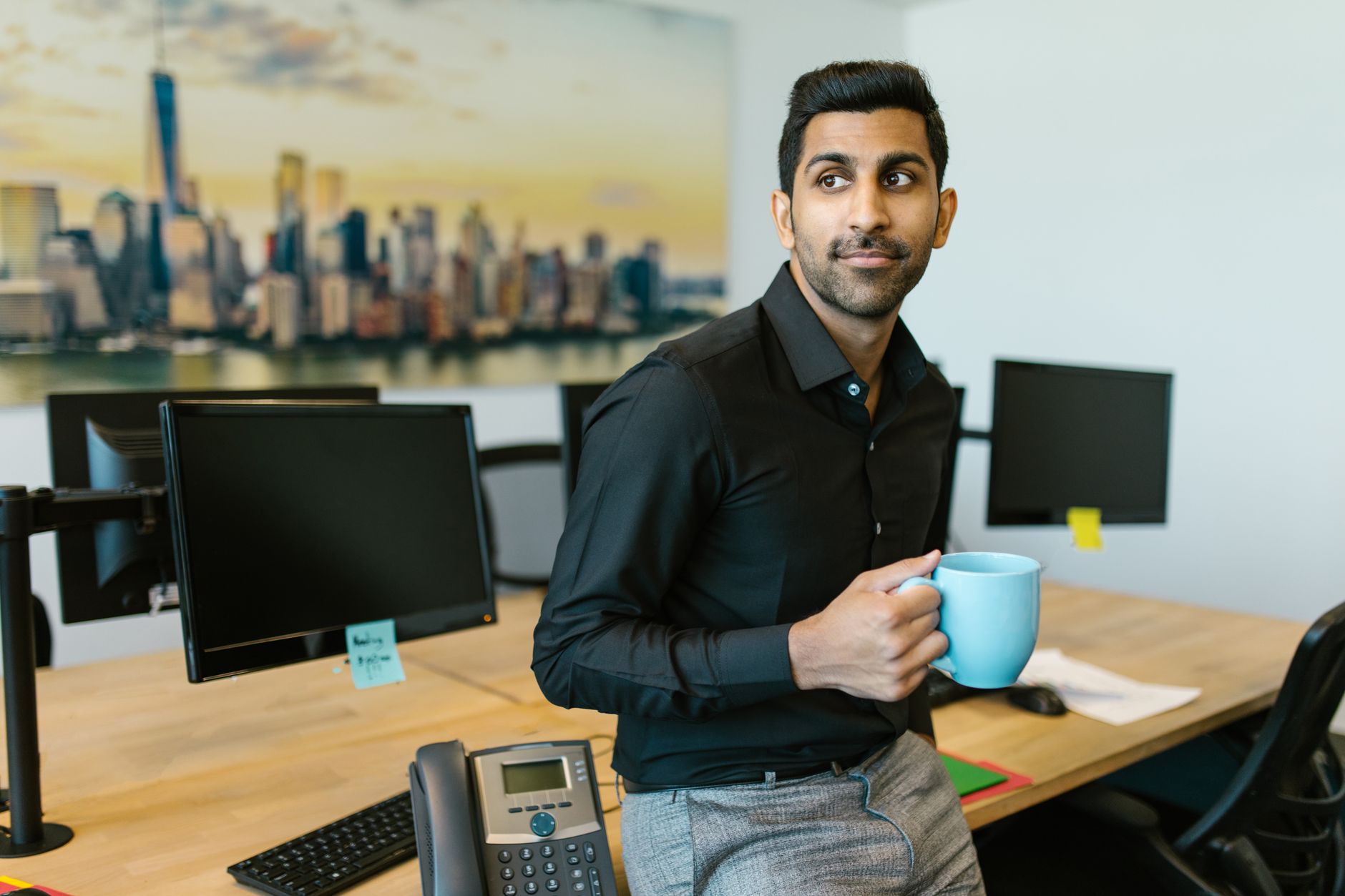 Confident Indian businessman enjoying a coffee break in a modern office space.