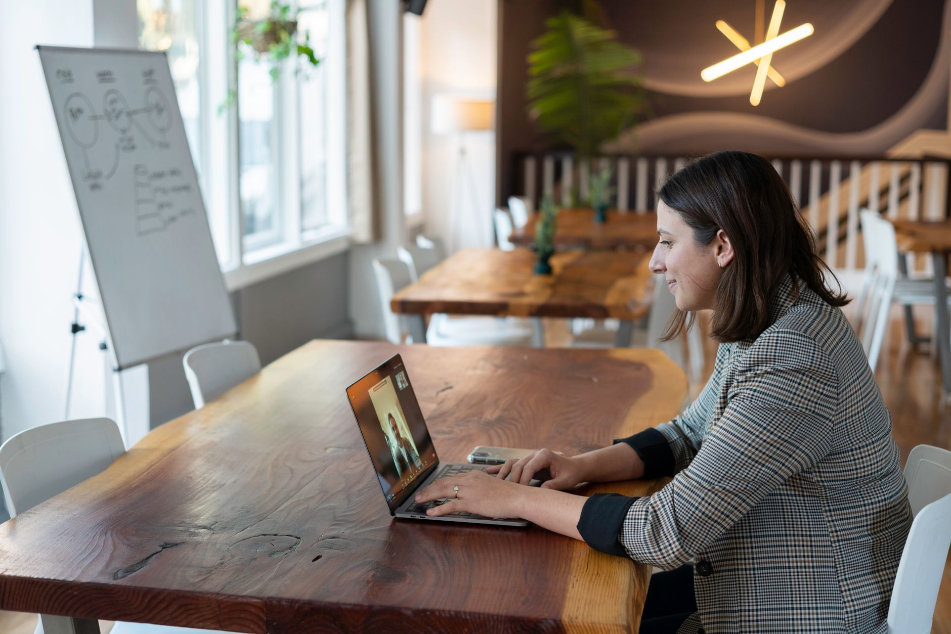Businesswoman engaged in a video call in a stylish, modern office setting with natural light.