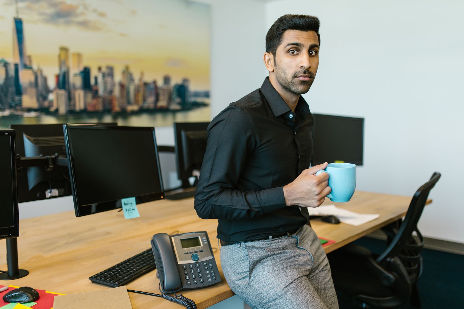 Professional man enjoying a cup of coffee while taking a break in a modern office setting.