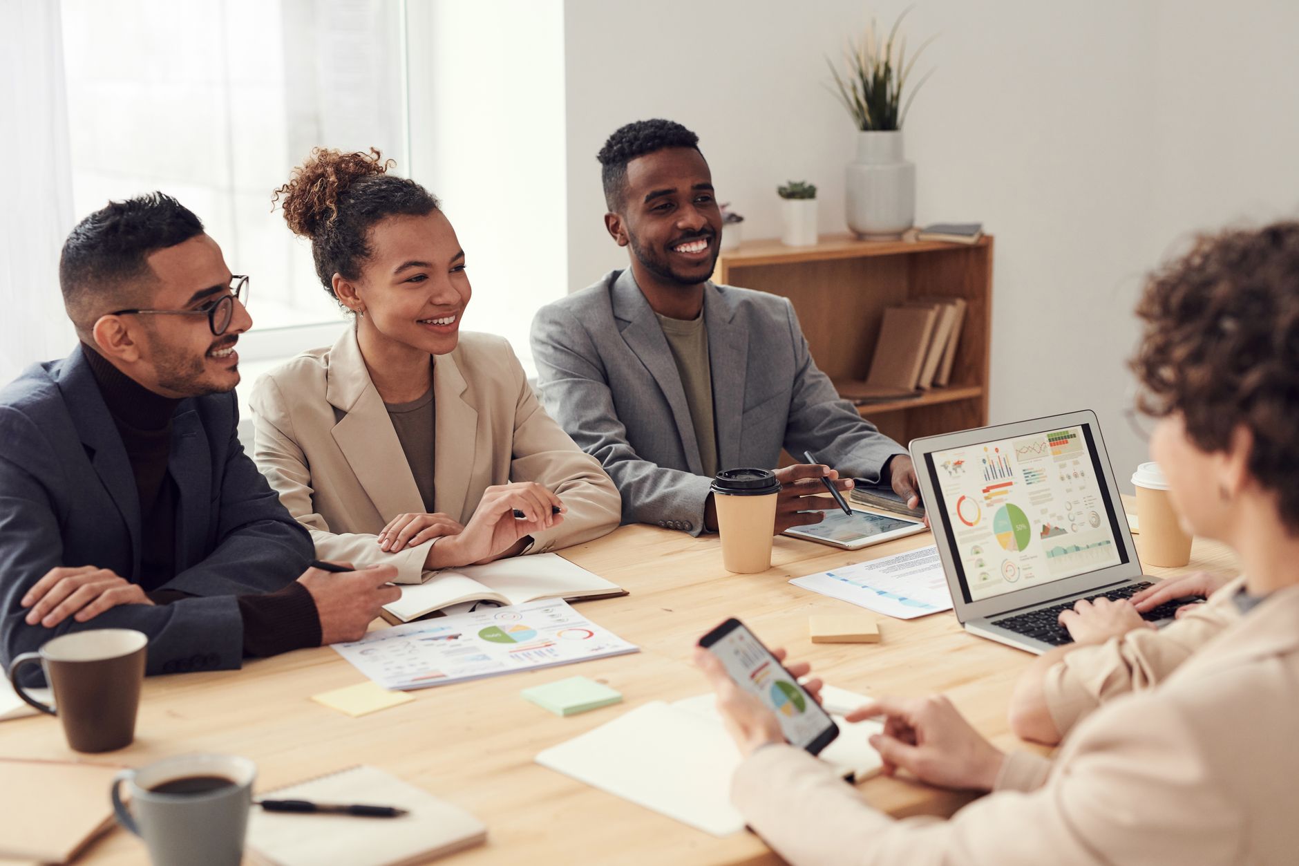 Young professionals discussing work at a conference table with technology and documents.