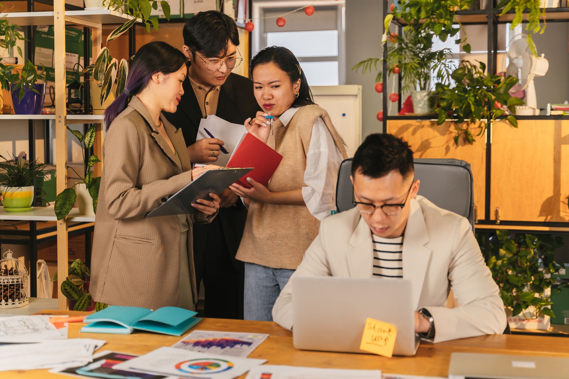 Group of young professionals collaborating in a modern, plant-filled office.