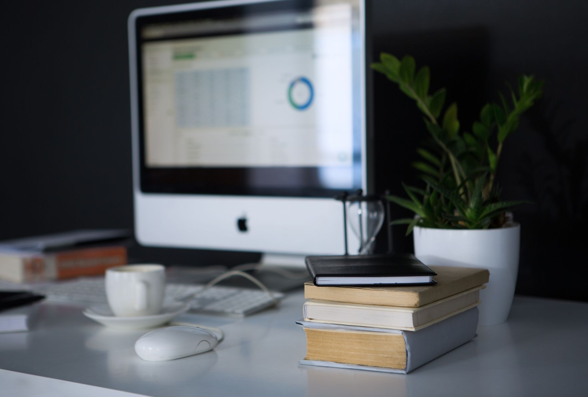 A sleek modern office setup featuring a computer, books, and a coffee cup on a desk.