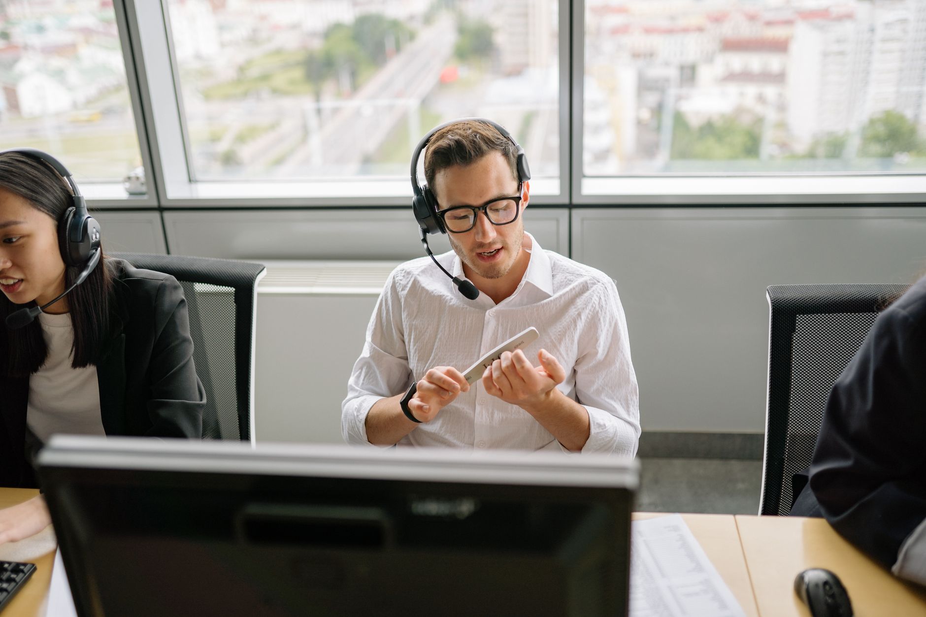 Call center agents wearing headsets and working at their desks in a modern office setting.