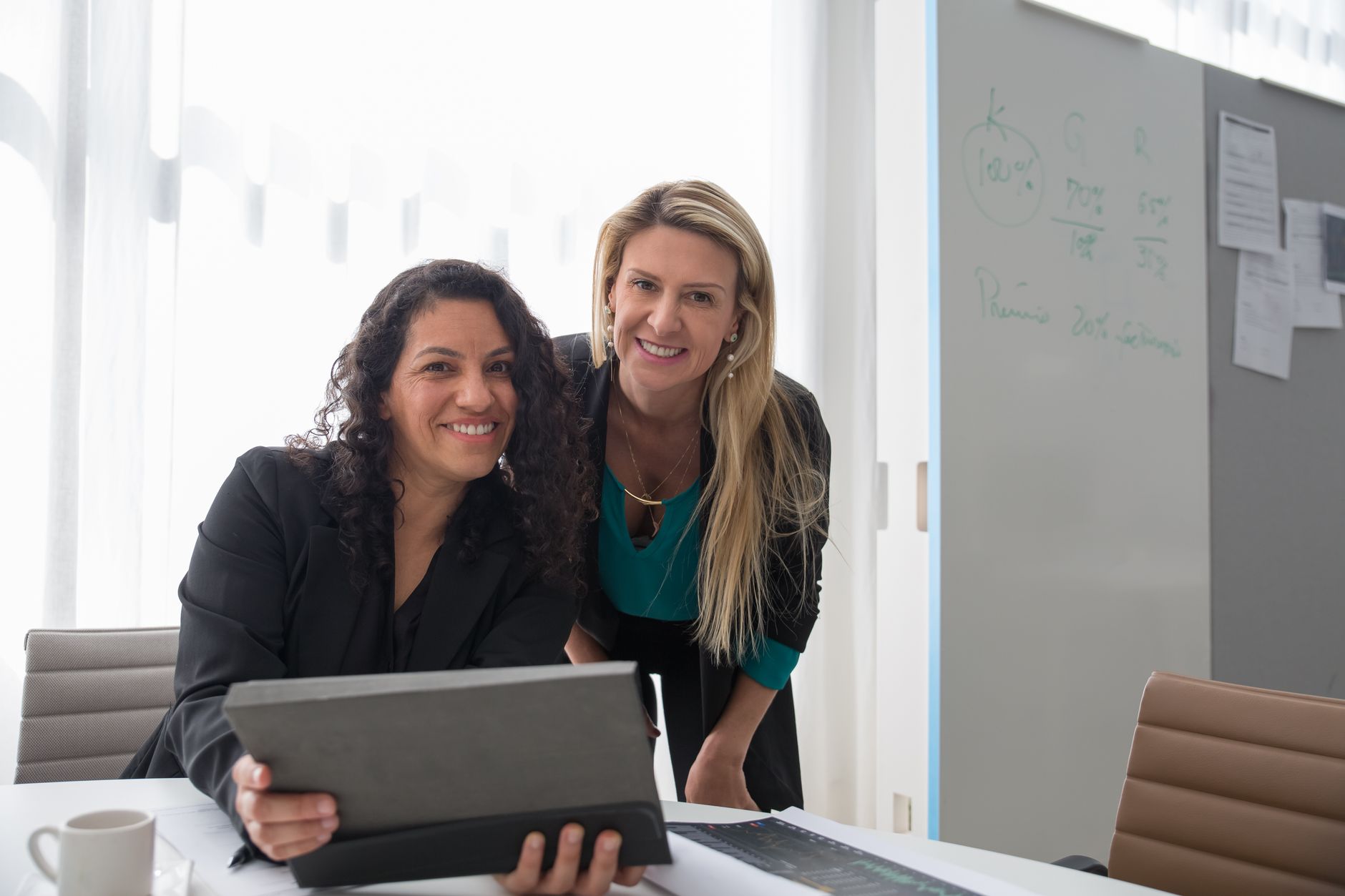 Smiling professional women collaborating in a bright and modern office setting.