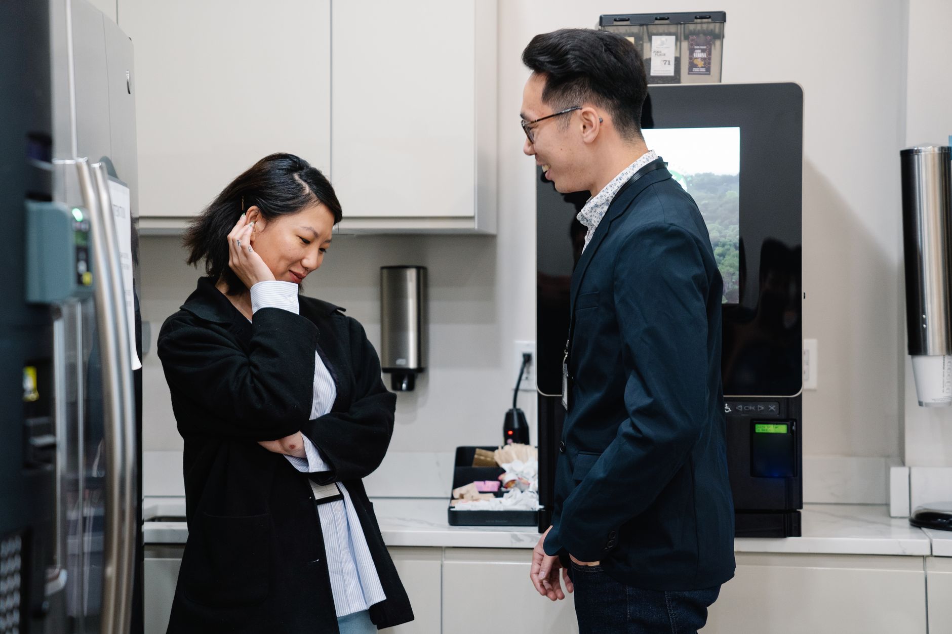 A candid moment of a man and woman talking in a stylish kitchen environment.