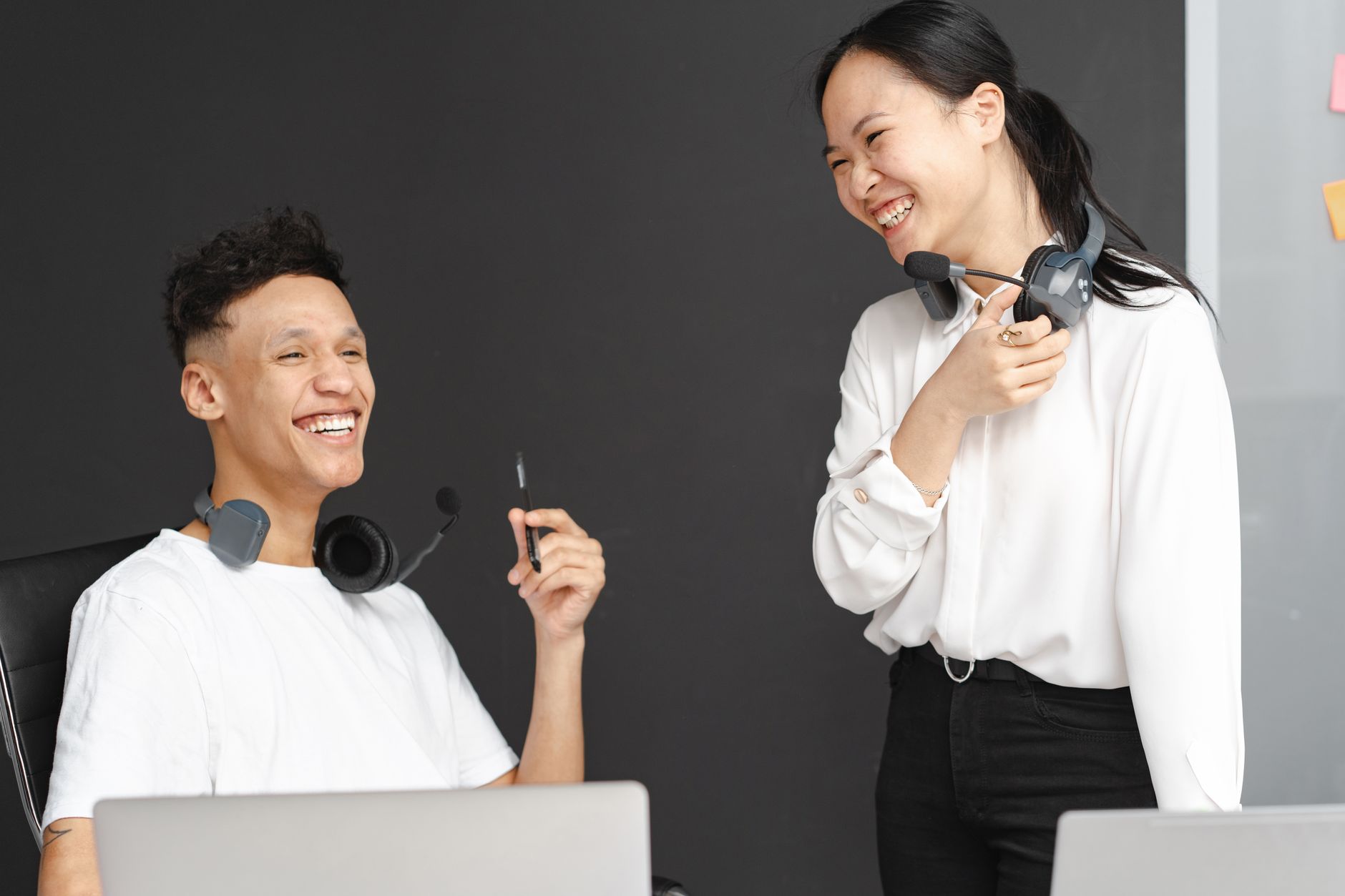 Two cheerful call center agents talking and laughing during a work break.