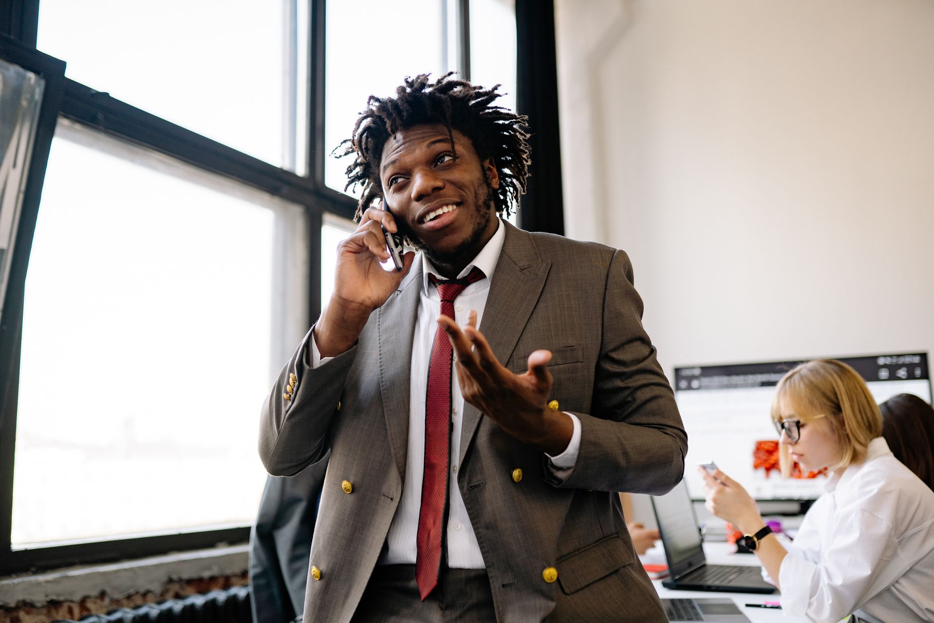 Professional businessman smiling while talking on the phone in an office setting.