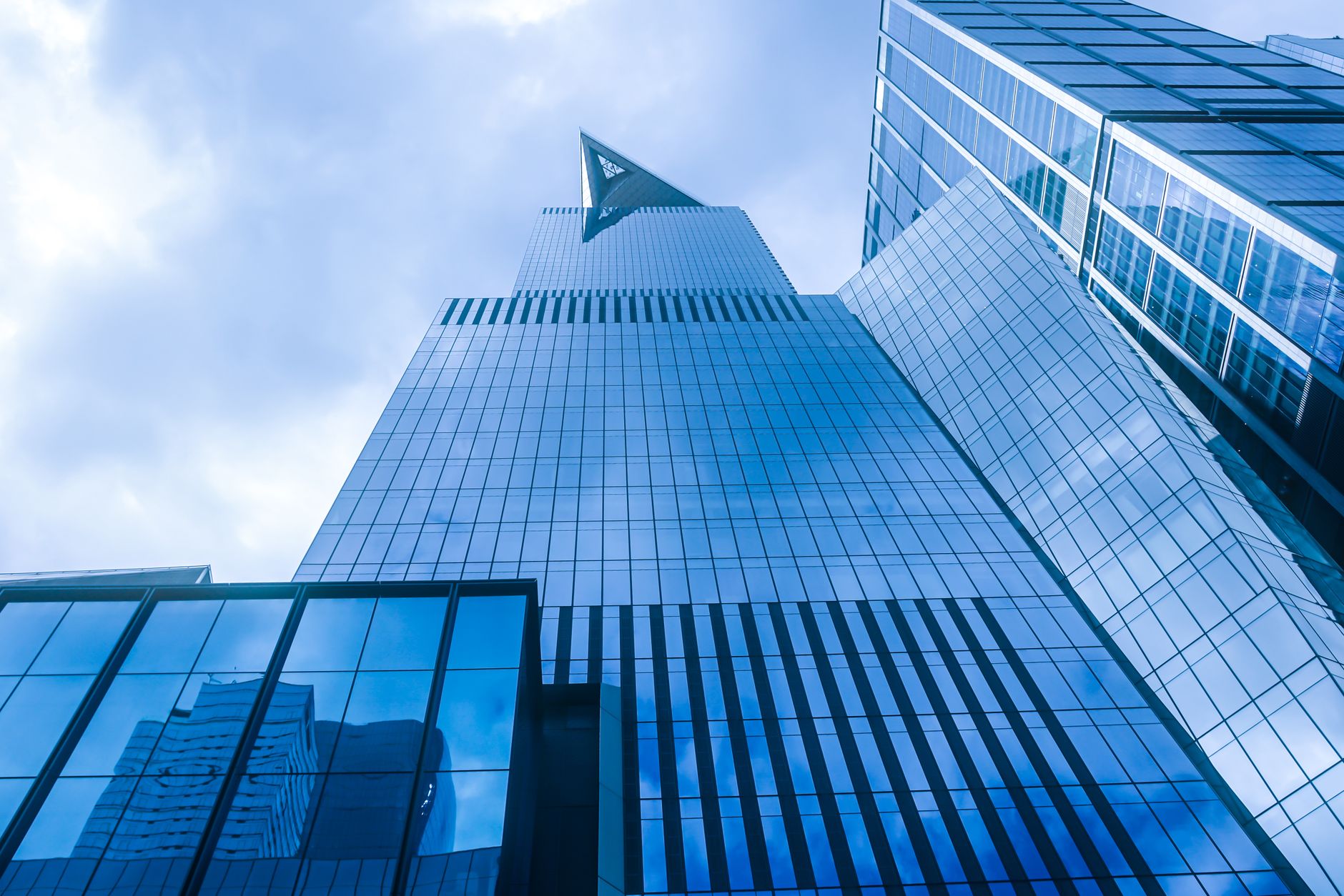 A stunning view of a modern skyscraper reflecting the New York City skyline in blue hues.
