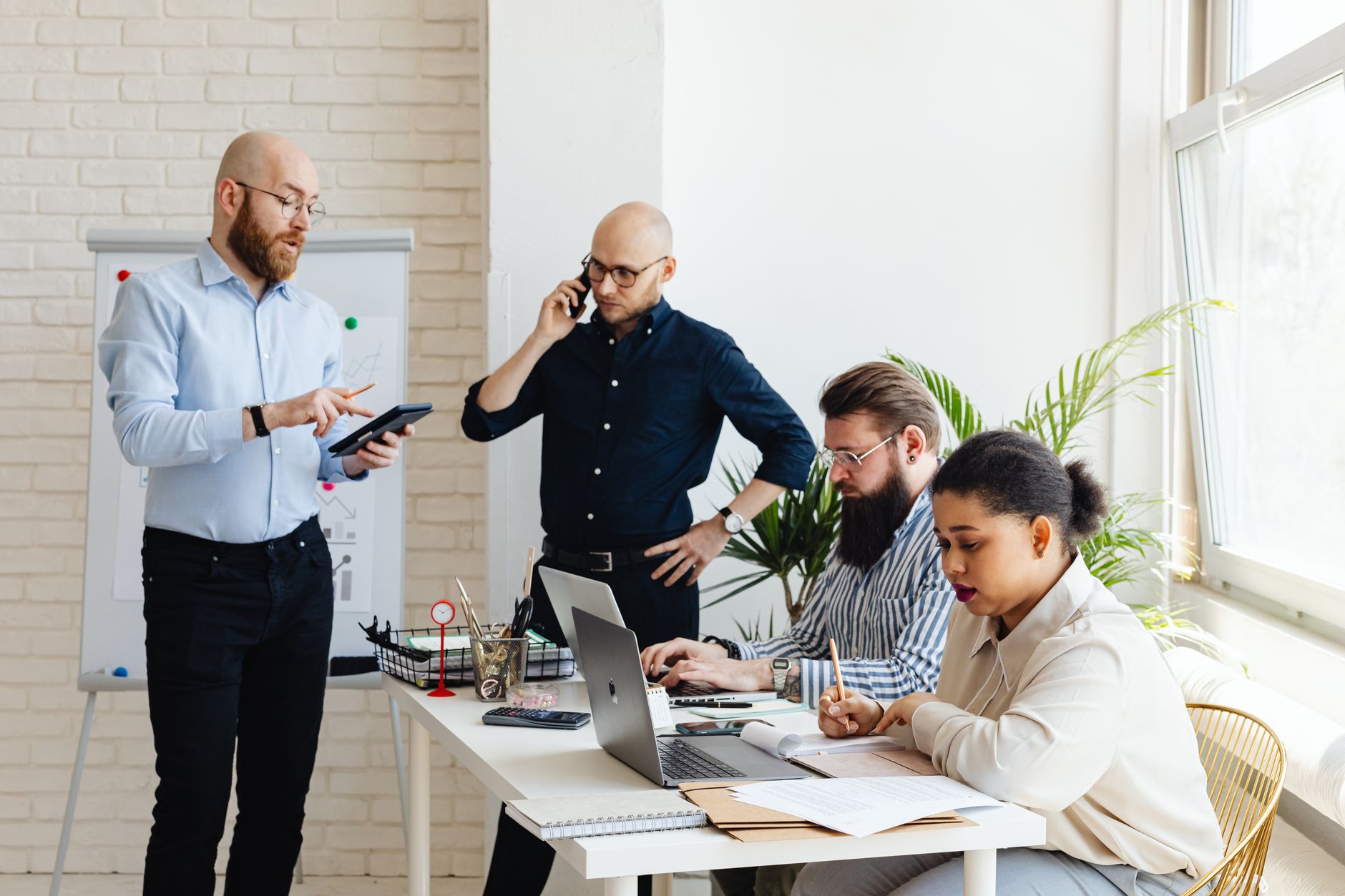 A diverse team of professionals collaborating in a modern office setting with laptops and notebooks.