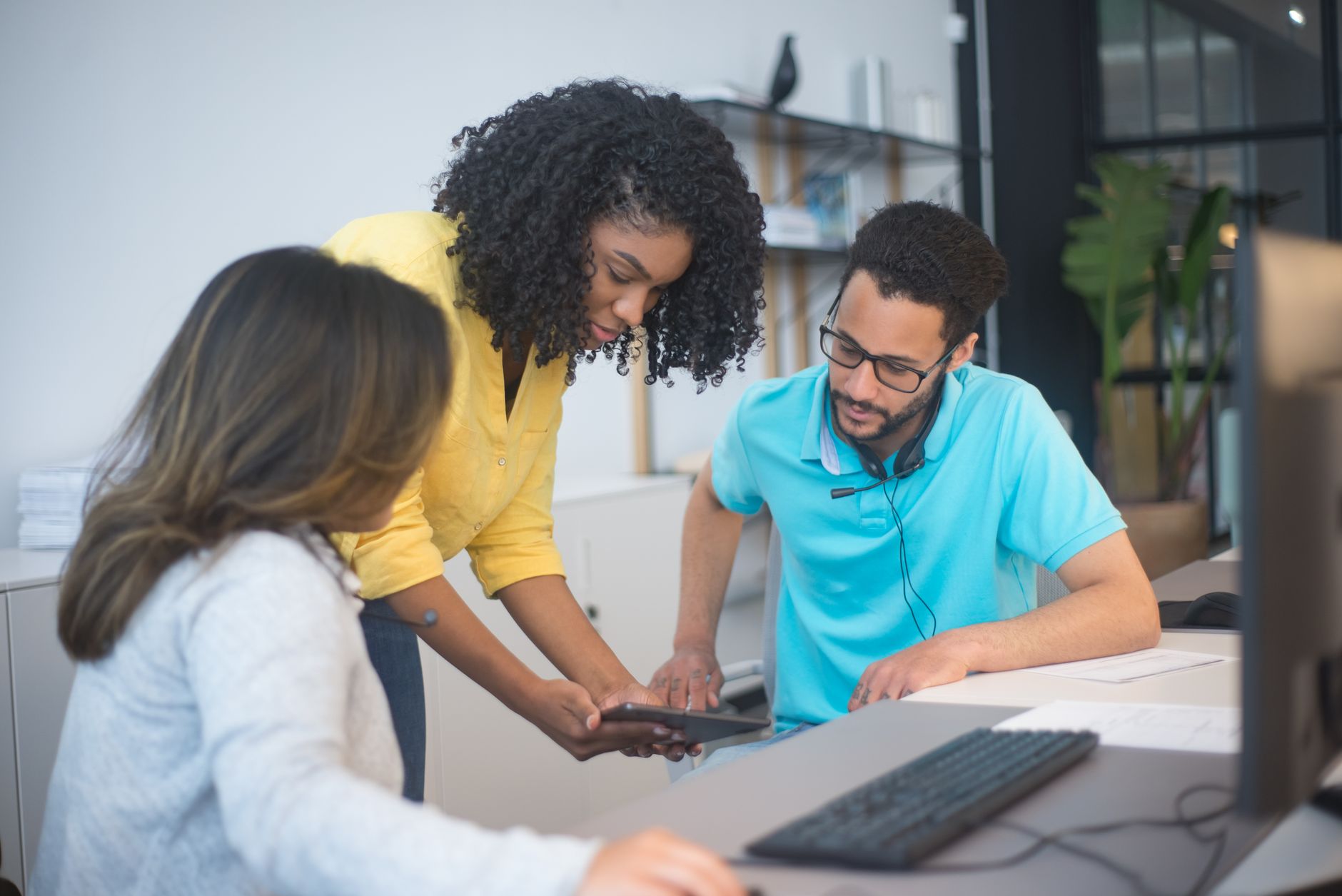 Three diverse colleagues collaborating in a modern office, focusing on teamwork and technology.