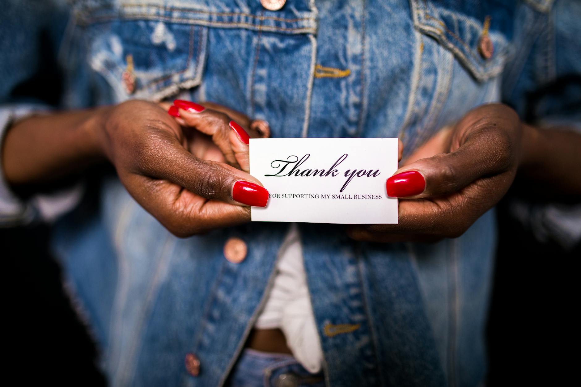Close-up of a hand holding an inspiring sign encouraging small businesses support.