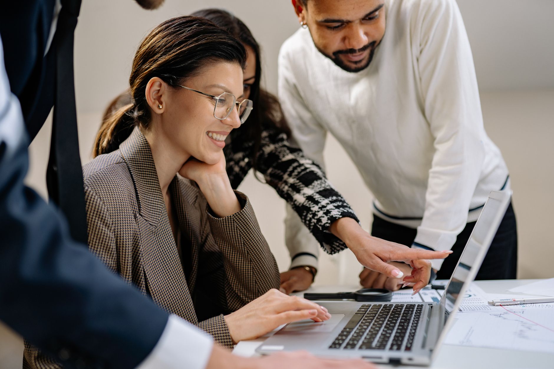 Diverse group of adults working together on a laptop in an office setting.