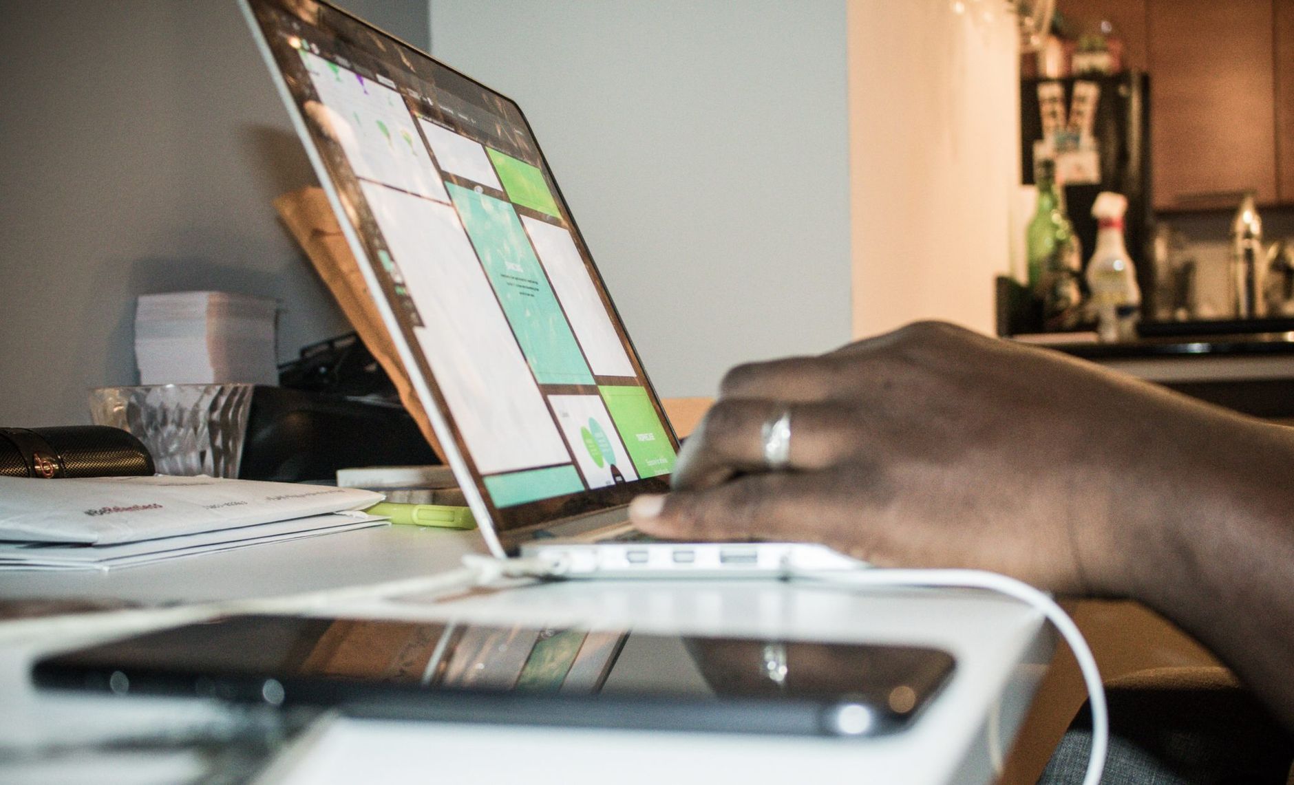 Focused setup of person working on a laptop in a home office environment with technology and documents.