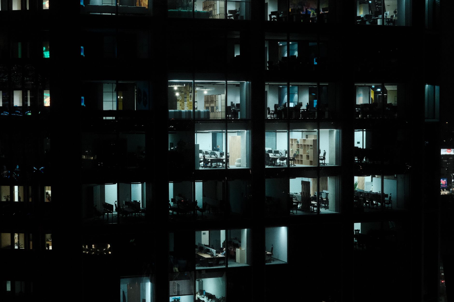 A nighttime view of a modern office building in Warsaw with illuminated interiors.