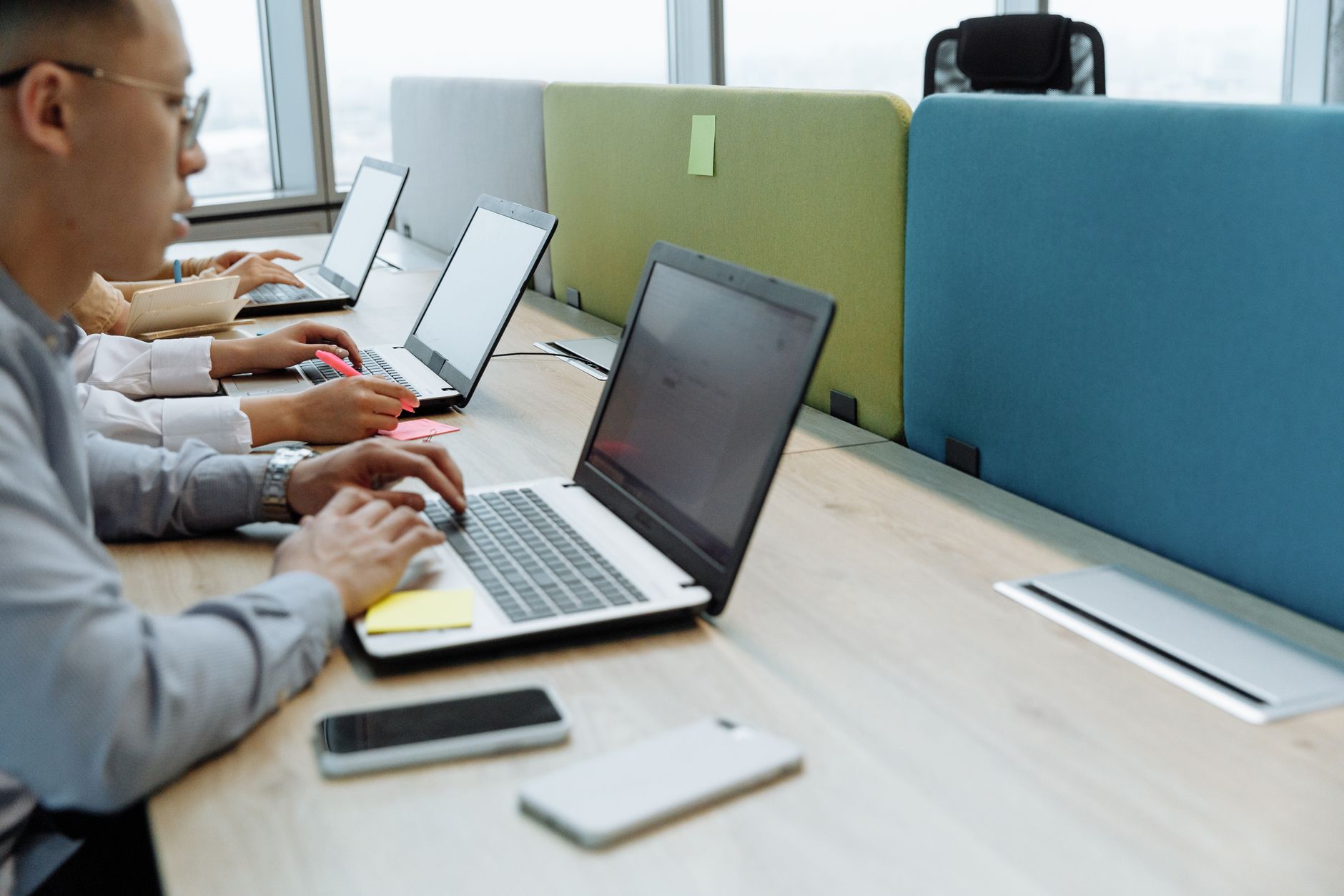 Colleagues working diligently at shared desks with laptops in a modern office space.