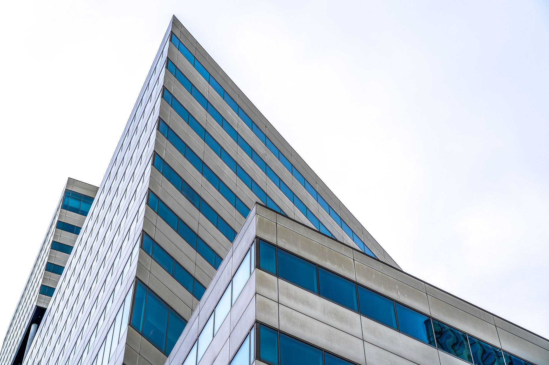 Low angle view of a modern skyscraper showcasing geometric designs and urban architecture against the sky.
