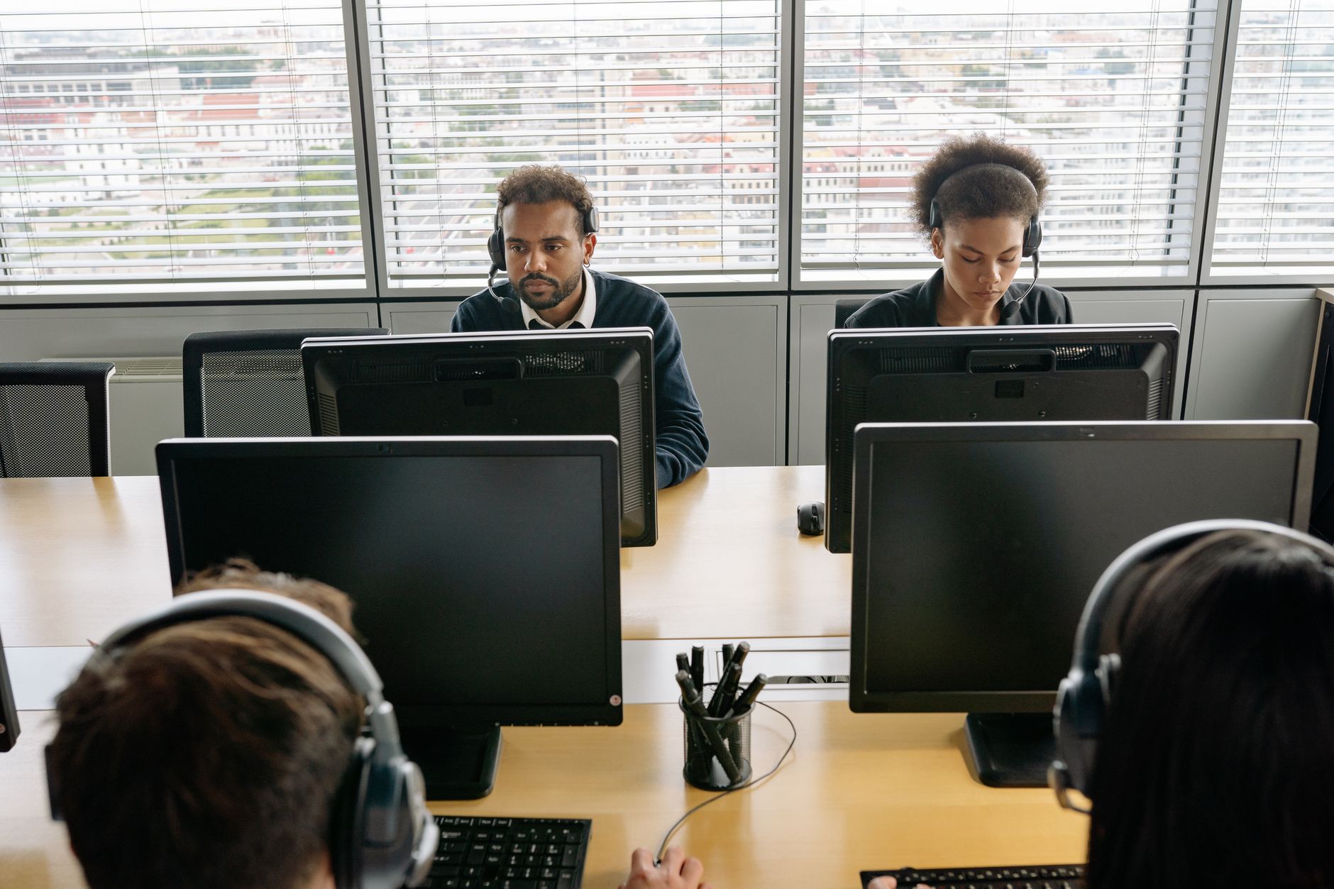 Group of call center agents working on computers in an office environment.