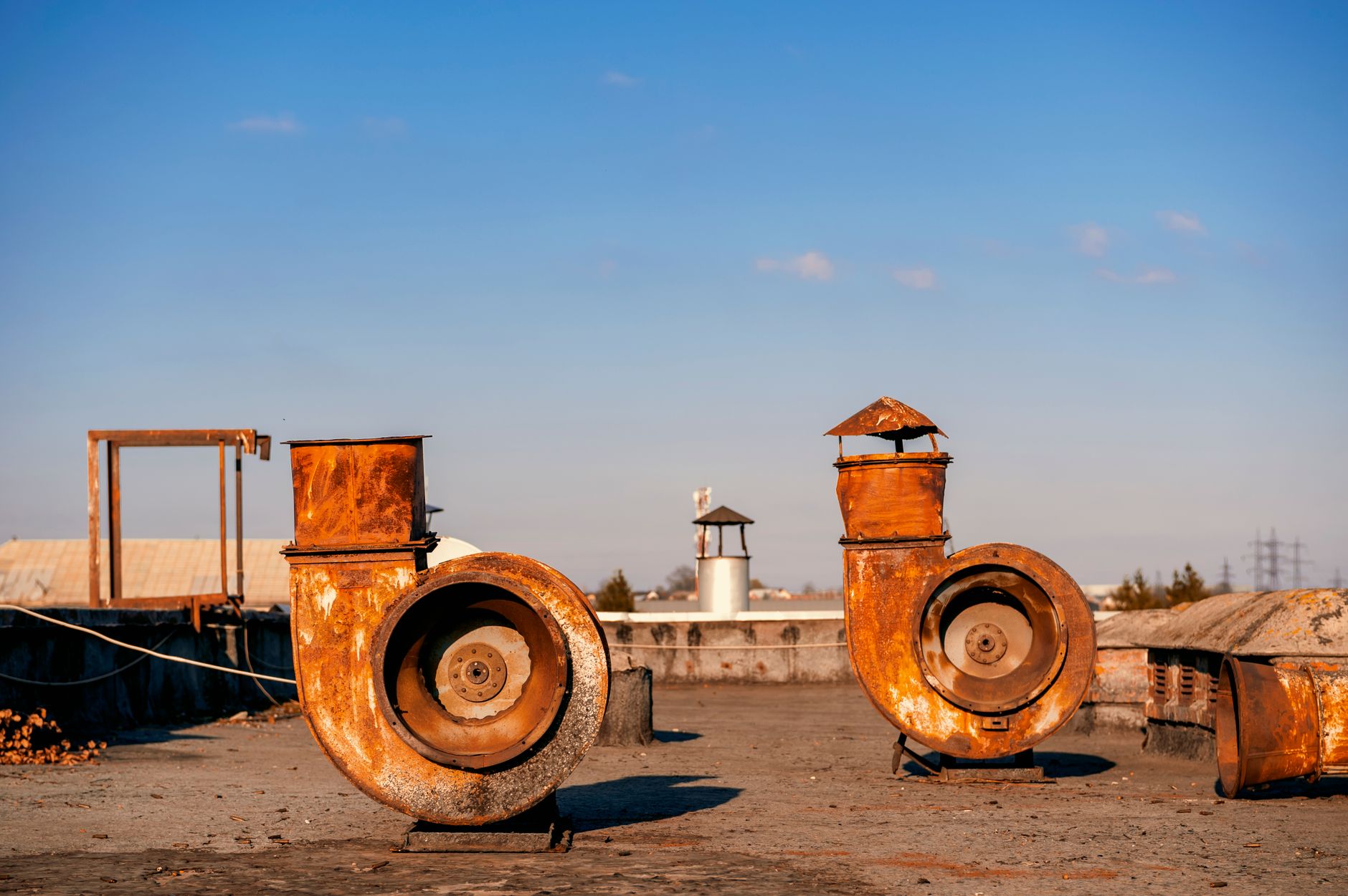 A pair of rusty industrial vent pipes on a rooftop on a sunny day in Lviv, Ukraine.