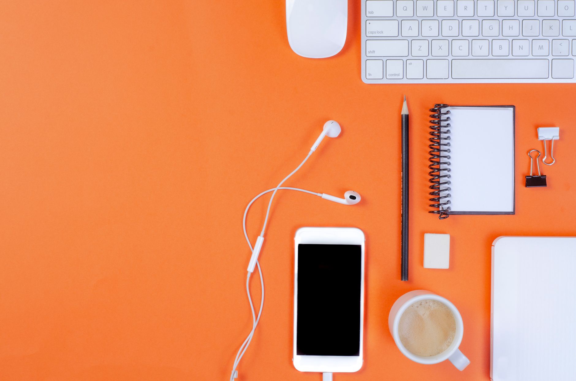 A stylish top view of office essentials on a vibrant orange background for remote work inspiration.